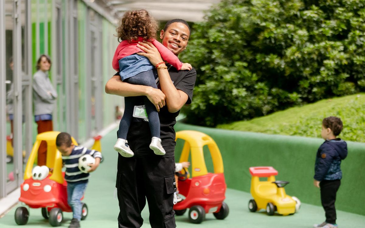 Educateur de jeune enfant titulaire du CAP AEPE portant un enfant en crèche